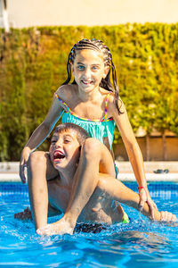 Two kids playing in a pool in a sunny day on vacations.
