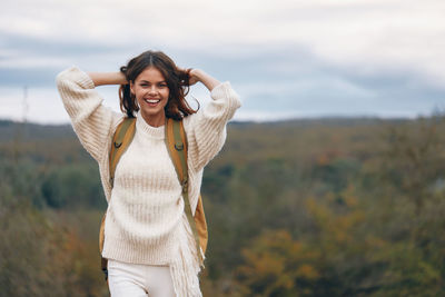 Young woman standing against sky