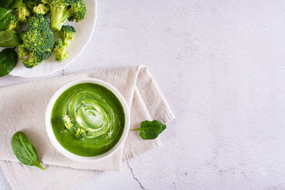 Fresh broccoli puree soup in a bowl on the table. vegetarian food. top view