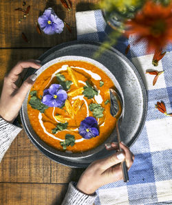 Cropped hand of person holding food in bowl on table