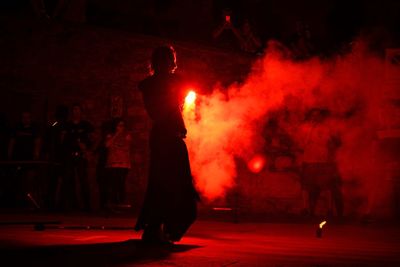 Rear view of man with firework standing on footpath at night 