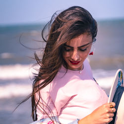 Close-up of smiling young woman looking down standing on beach