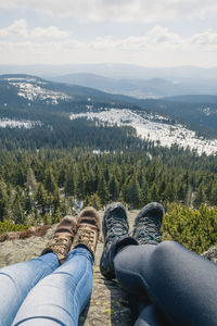 Low section of people on mountain against sky