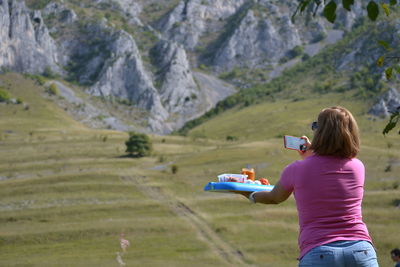 Rear view of woman holding food standing on landscape