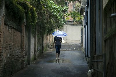 Woman walking in alley with striped umbrella in town
