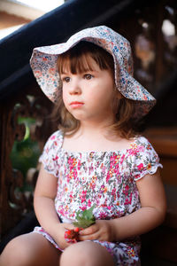 Girl looking away while sitting outdoors