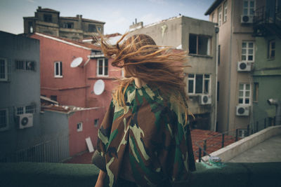 Woman standing by buildings in city