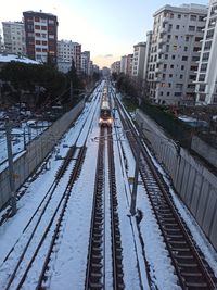 Railroad tracks amidst buildings in city during winter