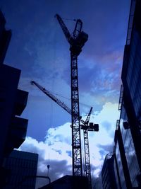 Low angle view of crane against cloudy sky