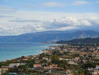 Aerial view of townscape by sea against sky