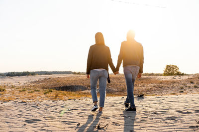 Rear view of couple walking against sky