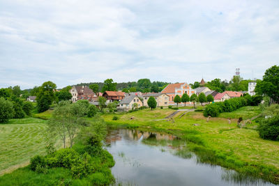 Scenic view of river by buildings against sky