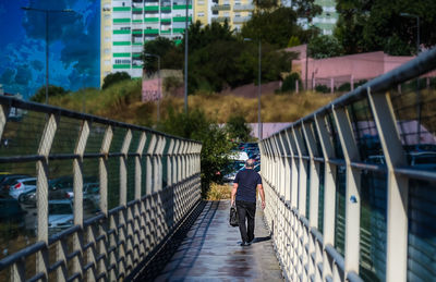 Rear view of man walking on footbridge