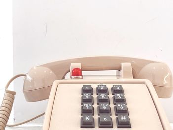 High angle view of telephone booth on table against white wall