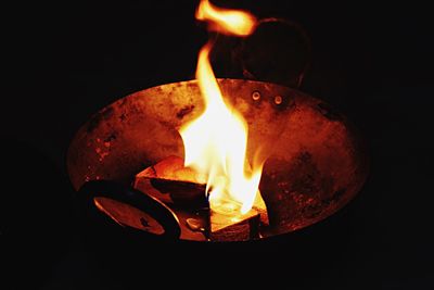 Close-up of burning candle against black background