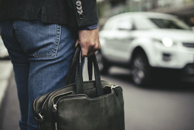 Midsection of businessman carrying briefcase on street
