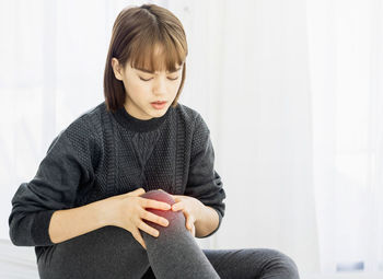 Young woman looking away while sitting at home