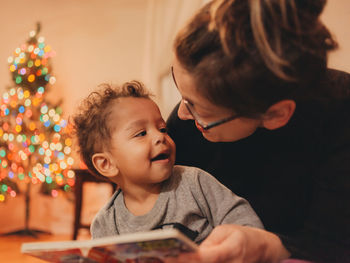 Close-up of son looking at mother reading book at home