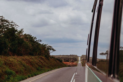 Road by trees against sky