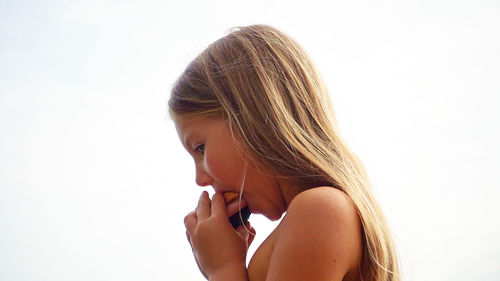 Close-up of girl eating food by clear sky