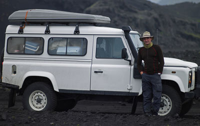 Full length portrait of man standing on car