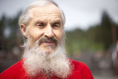 Old generation. portrait of senior bearded man standing outdoors and looking at camera with sad look