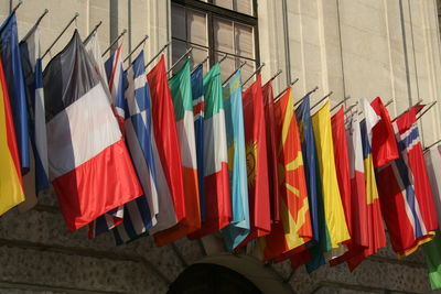 Multi colored flags hanging against wall in city