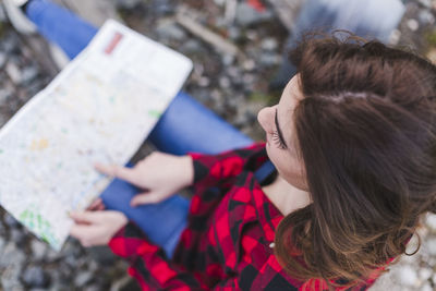 Woman reading map while sitting outdoors