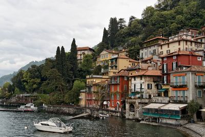 Boats moored on river by trees against sky