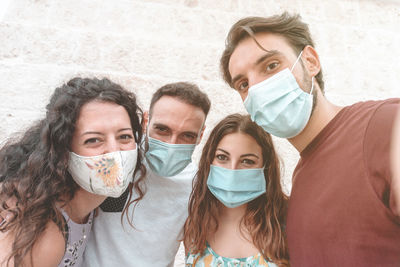 Portrait of smiling couple wearing flu mask standing against wall