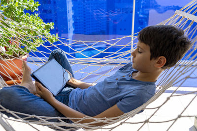 Rear view of boy sitting on mobile phone