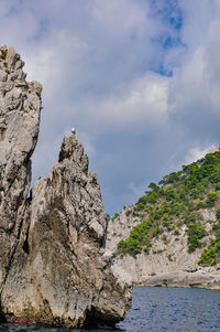 Low angle view of rock formation in sea against sky