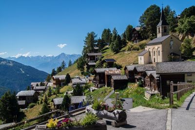 Church and village by trees against blue sky