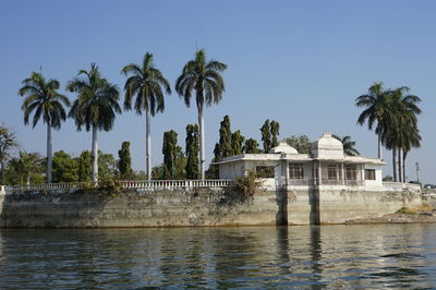 Palm trees by lake against historical building