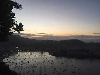 Scenic view of river by silhouette mountains against clear sky