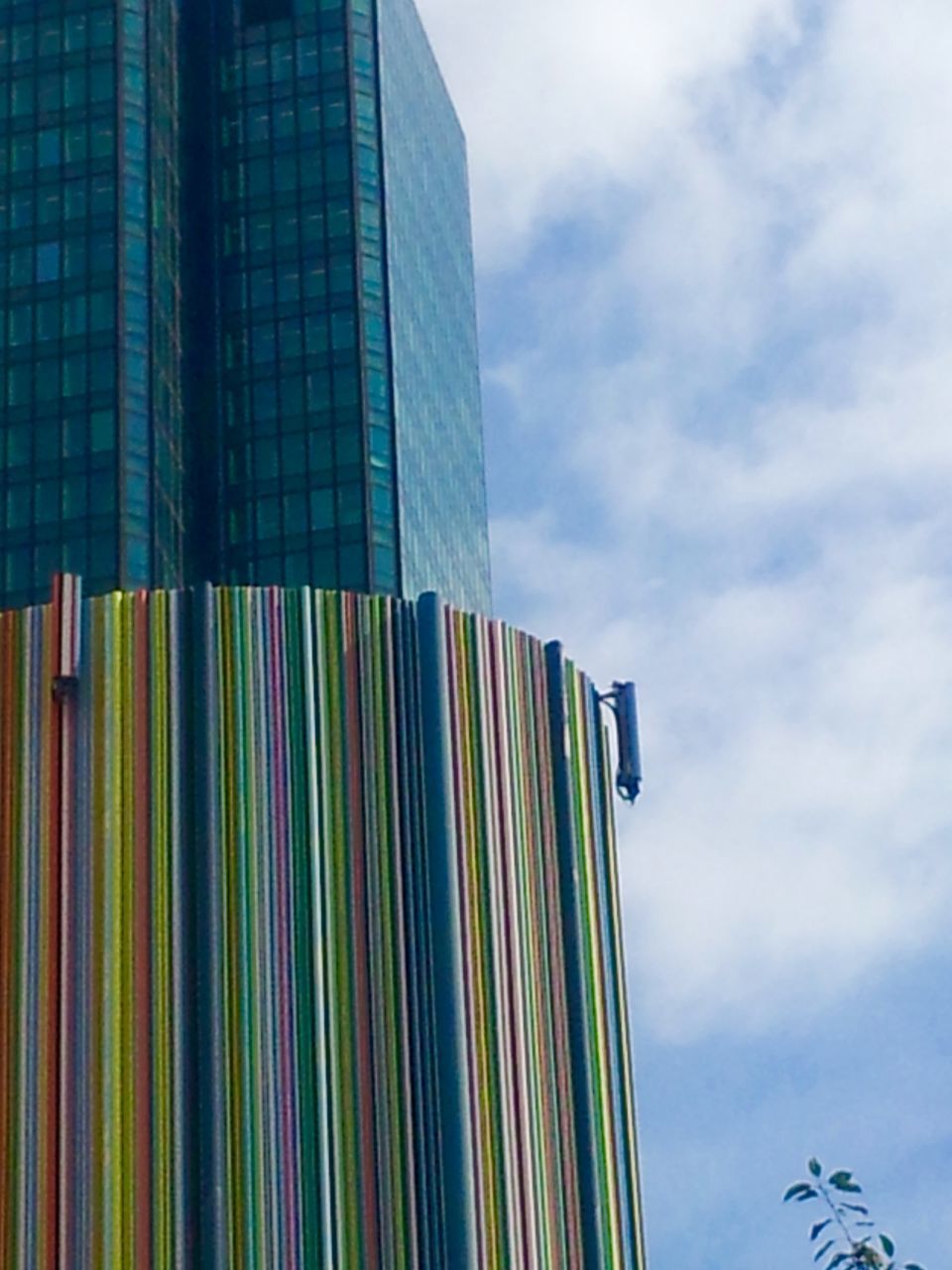 low angle view, architecture, building exterior, built structure, modern, sky, office building, city, skyscraper, tall - high, multi colored, blue, cloud - sky, tower, american flag, flag, building, cloud, outdoors, day