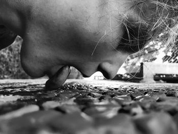 Close-up of young woman licking footpath