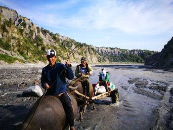 People riding bullock cart against mountain
