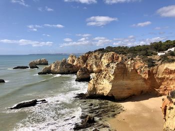 Rock formations on shore against sky