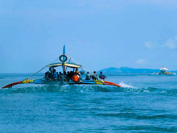 Man rowing boat in sea against sky