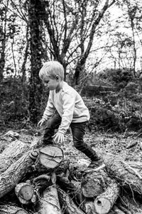 Full length of boy sitting in forest