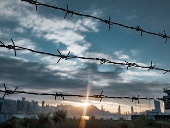 Low angle view of fence against sky during sunset