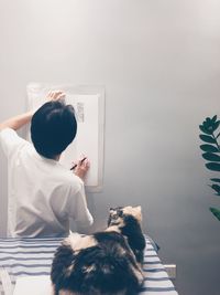 Rear view of woman with dog sitting at home