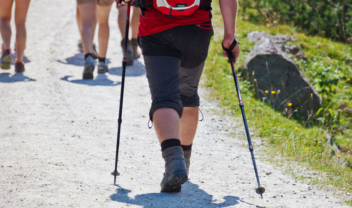 Low section of man with hiking poles walking on trail at swiss alps