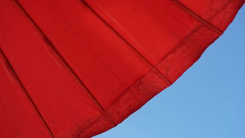 Low angle view of red umbrella against clear sky