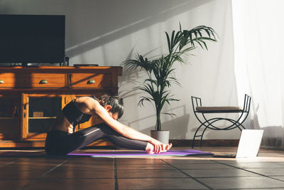 Young caucasian brunette woman stretching at home.