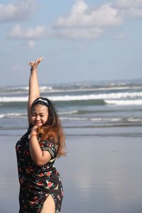 Woman gesturing while standing on shore at beach