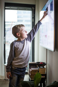 Boy touching digital display of smart television set at modern home