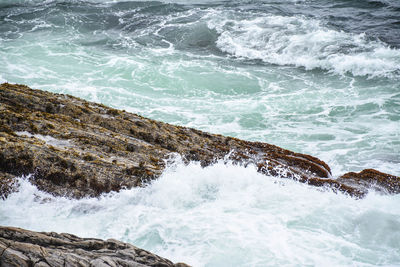 Scenic view of sea waves crashing against rocks