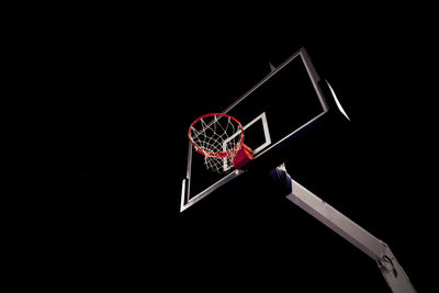 Low angle view of basketball hoop against black background